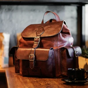 Explorer Large Backpack in vintage brown leather placed on a wooden table, showcasing its structured design and rich leather texture.