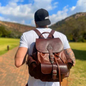 Explorer Large Backpack in vintage brown leather, displayed outdoors, emphasizing its rugged and adventure-ready design.