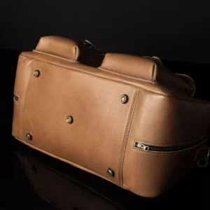Bottom view of Marcella Overnight Duffle Bag in tan leather, featuring protective brass feet for durability.