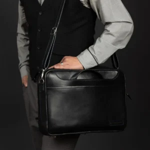 Side view of Astin Sleek black leather laptop bag, showcasing sturdy leather handles and slim profile.