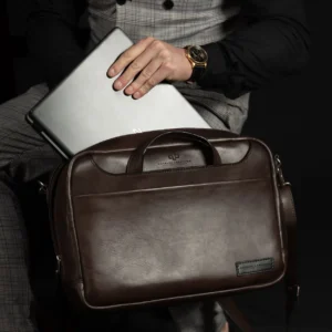 Seated model with Astin Sleek brown leather laptop bag, showcasing its ergonomic design and soft leather finish.