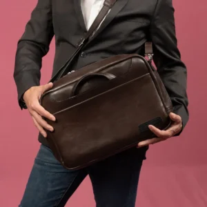 Model carrying the Astin Sleek brown leather laptop bag with shoulder strap, highlighting its versatile carrying options.