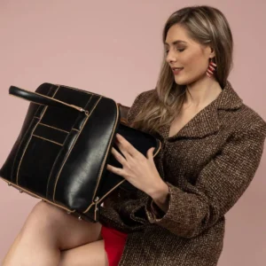 The women's Reagan Euro black leather laptop bag is styled by a model, highlighting its elegant and professional look.