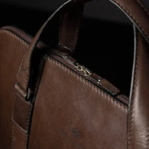Close-up of Reagan Euro brown leather laptop bag handles, featuring silver hardware and reinforced stitching.