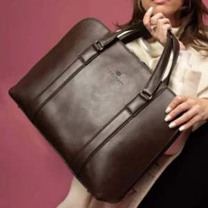 Model carrying the women's Reagan Euro brown leather laptop bag, emphasizing its structured silhouette and elegant design.