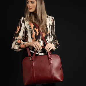 Model posing with the women's Reagan Euro ruby red leather laptop bag, highlighting its bold color and refined leather texture.