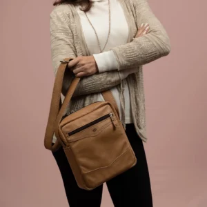 Women's Montrose Sling Bag in tan leather, worn crossbody by a female model, illustrating its sleek and practical design.