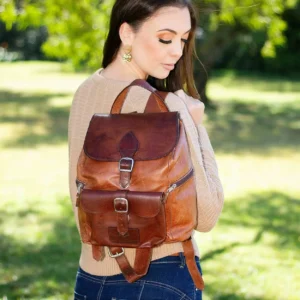 Women’s Explorer Medium Backpack in vintage brown leather, held by model, showcasing the structured pockets and soft body.