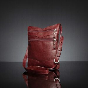 Angled shot of Women's Dakota Sling Bag in ruby red, showcasing stitching and a sleek, elegant shape.