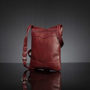 Close-up of Women's Dakota Sling Bag in ruby red, featuring a back zip pocket and durable metal fittings.