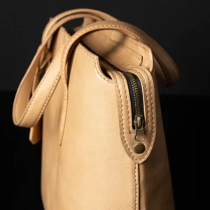 Tan leather tote bag with open zip closure, showing the premium full-grain leather finish and spacious interior.