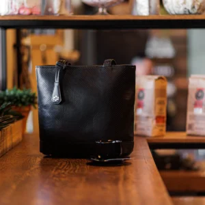 Women's black genuine leather tote bag in a lifestyle setting, showcasing elegant basket pattern and spacious design for daily use.