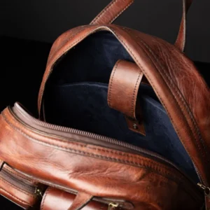 Inside view of Franklin men's leather laptop backpack, featuring a royal blue suede-lined laptop compartment and organization pockets.