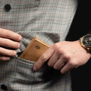 Man holding the Ashford Trifold Wallet in tan leather, highlighting its compact, full-grain leather finish in everyday use.
