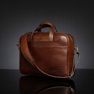 Angled side view of Astin Sleek polished brown leather laptop bag, emphasizing its structured form and polished detailing.
