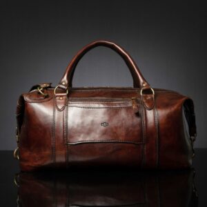 Back view of Mansfield Duffle Bag in vintage brown leather, featuring a zippered compartment and a leather sleeve for securing onto a luggage handle.
