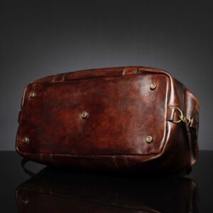Bottom view of Mansfield Duffle Bag in vintage brown leather, showcasing protective brass feet for durability and stability.