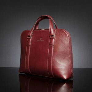Side view of women's Reagan Euro ruby red leather laptop bag, showcasing its structured design and polished finish.