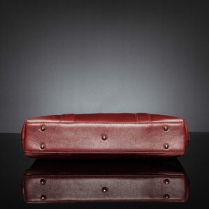 Bottom view of women's Reagan Euro ruby red leather laptop bag, showcasing a reinforced base with protective metal feet.