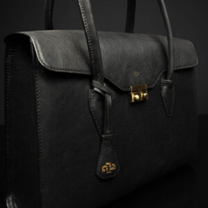 Side view of women's black leather laptop tote bag with gold-tone hardware and structured design.