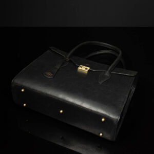 Bottom view of women's black leather laptop tote bag, featuring gold-tone protective feet for durability.