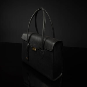 Angled view of women's black leather laptop tote bag, showing sleek silhouette and premium finish.