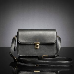 Women's Cressida Black leather sling bag with a structured design, gold-tone clasp, and adjustable strap for a timeless look.