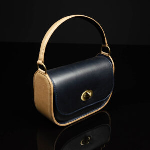 Luminara two-tone leather handbag with navy body and tan handle, showing its classic structured profile and premium cowhide finish.