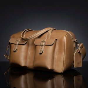 Angled view of Marcella Overnight Duffle Bag in tan leather, showcasing it's shape and 2 front pockets.