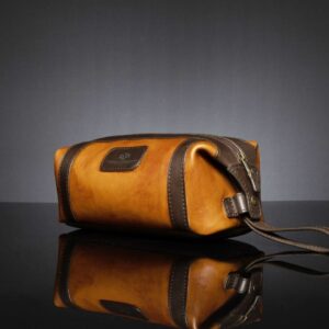 Side view of Mansfield Toiletry Bag in brown and tan leather, showcasing the expandable press-stud opening.
