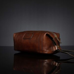 Side view of Mansfield Toiletry Bag in polished brown leather, highlighting the press-stud opening for flexible storage.