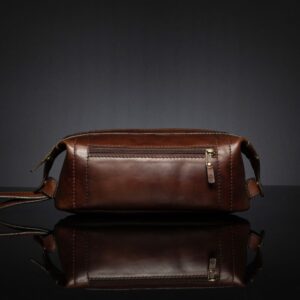 Back view of Mansfield Toiletry Bag in polished brown leather, featuring a zippered back pocket for added convenience.