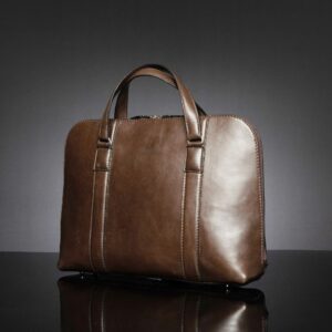 Angled view of Reagan Euro brown leather laptop bag, highlighting refined stitching and durable leather handles.