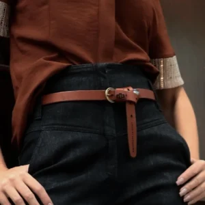Women’s rich tan skinny leather belt, styled with jeans for a modern and effortless look.